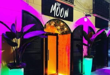 The Moon gay bar in Barcelona. Tropical decor, neon lights, and plants create a vibrant atmosphere. A must-visit spot for gay travelers.