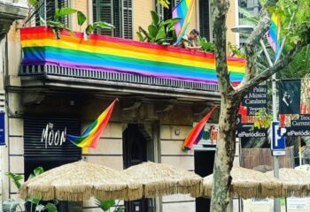 The Moon Tropical gay bar in Barcelona. Rainbow flags decorate the entrance. Gay travel destination. Umbrellas outside.