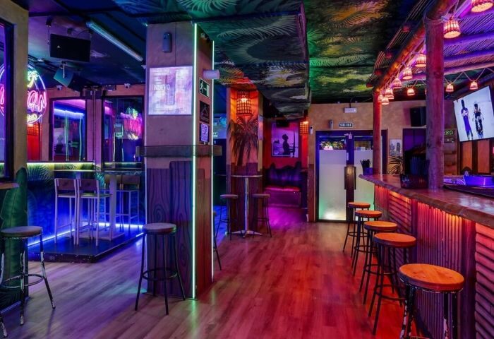 Interior of The Moon Tropical gay club in Madrid. A vibrant bar with tropical decor, neon lights, and a lively atmosphere for gay travelers.