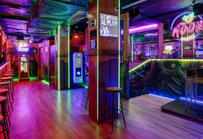 Inside The Moon Tropical Gay Club in Madrid, featuring neon lights, tropical decor, a bar, and seating for gay travelers.