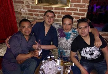 Gay men enjoying The New Jalisco Bar experience. Friends pose with Corona beers at this gay-friendly bar, a must-visit for gay travel.