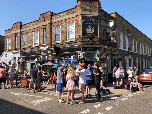 The Old Ship Gay Bar in London. People gather outside the pub on a sunny day, enjoying drinks and socializing. A popular spot for gay men's travel.