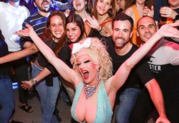 Drag queen performing at The Oxford Hotel Sydney, a gay-friendly venue. Crowd of smiling people in the background. Gay travel advice.