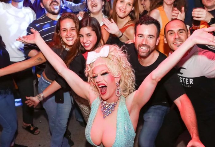 Drag queen performing at The Oxford Hotel Sydney, a gay-friendly venue. Crowd of smiling people in the background. Gay travel advice.