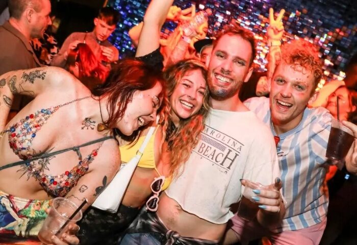 People at The Oxford Hotel Sydney. A group of smiling friends at a gay bar, enjoying drinks and a fun night out. Gay travel advice.