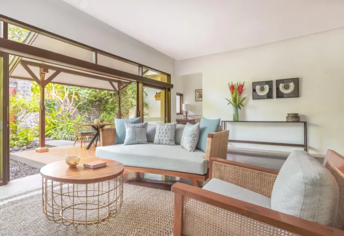 Living area at The Pavilions Bali, a gay-friendly hotel. Features stylish seating, a coffee table, and a view of the lush outdoor space.