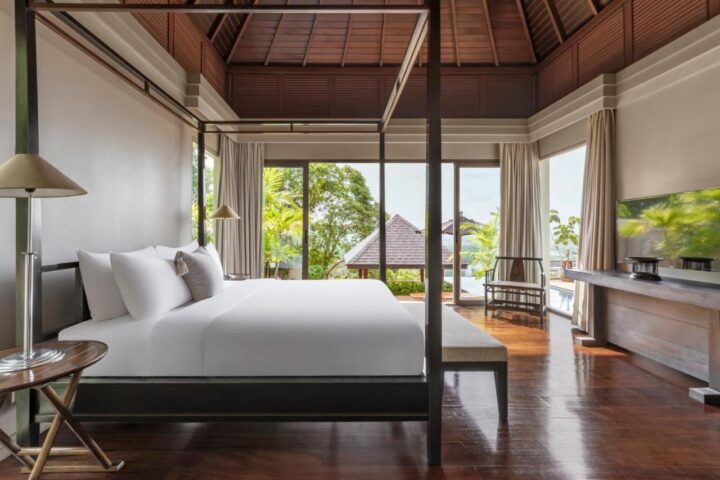 The Pavilions Phuket suite. Gay Phuket travel. Four-poster bed, wood floors, and a view of the pool. Luxury gay travel in Thailand.