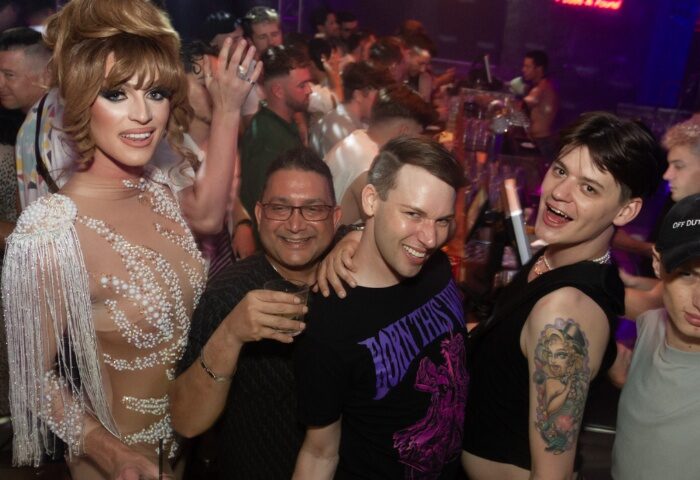 Inside The Peel Hotel Melbourne, a gay bar, drag queen and patrons pose for a photo. Gay travel advice for Melbourne, Australia.