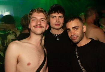 Three gay men pose at The Peel Hotel, Melbourne. Nightlife scene with green lighting. Gay travel advice.