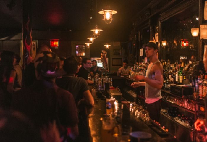 Interior of The Phoenix Gay Bar in New York. Bartender serving drinks at a busy bar. A popular gay bar and travel destination.