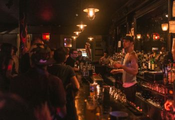 Interior of The Phoenix Gay Bar in New York. Bartender serving drinks at a busy bar. A popular gay bar and travel destination.