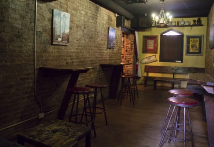 Interior of The Phoenix Gay Bar in New York. Brick walls, stools, benches, and artwork. A cozy spot for gay men travel advice.