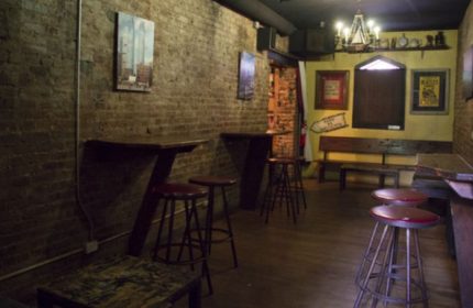 Interior of The Phoenix Gay Bar in New York. Brick walls, stools, benches, and artwork. A cozy spot for gay men travel advice.