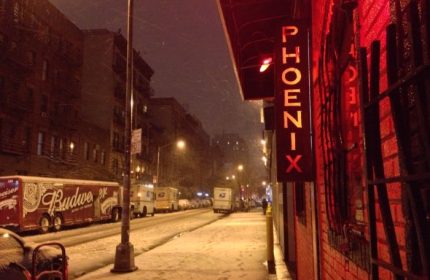 The Phoenix Gay Bar in New York City on a snowy night. Red neon sign. Gay travel advice. LGBTQ+ nightlife.