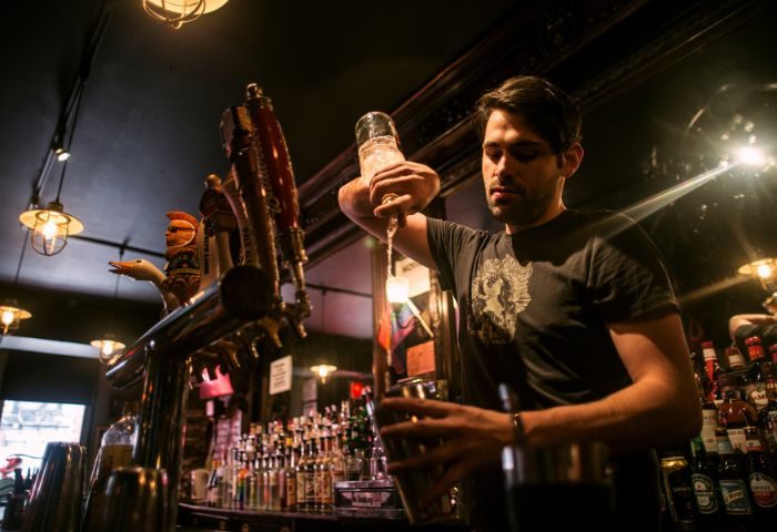 Bartender pours a drink at The Phoenix Gay Bar in New York. A gay bar popular for gay men travel advice in NYC.