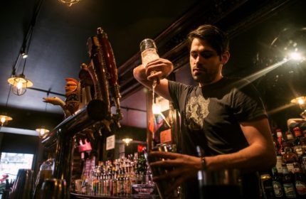 Bartender pours a drink at The Phoenix Gay Bar in New York. A gay bar popular for gay men travel advice in NYC.