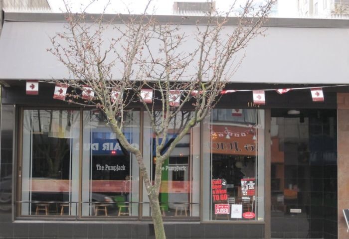 The Pumpjack Pub in Vancouver, a gay-friendly bar. Canadian flags adorn the awning. A tree stands in front of the entrance. Travel advice.