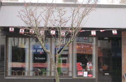 The Pumpjack Pub in Vancouver, a gay-friendly bar. Canadian flags adorn the awning. A tree stands in front of the entrance. Travel advice.