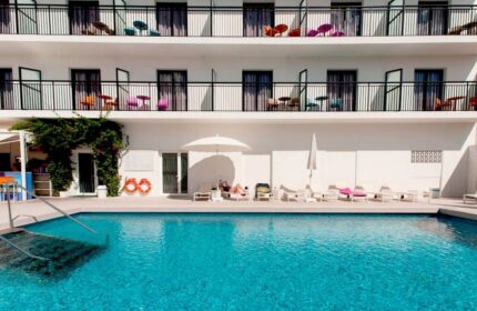 The Purple Hotel Adults Only: Pool view of the gay special hotel. Balconies, lounge chairs, and clear blue water. Gay travel destination.