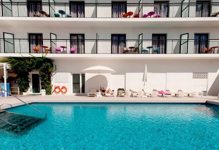 The Purple Hotel Adults Only: Pool view of the gay special hotel. Balconies, lounge chairs, and clear blue water. Gay travel destination.