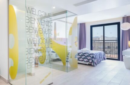 The Purple Hotel Ibiza Suite. Modern room with glass partition, purple accents, balcony. Gay-friendly hotel for special Ibiza holidays.