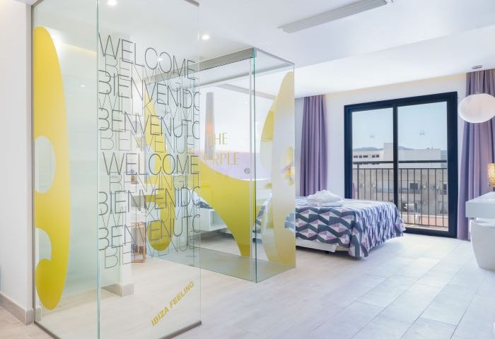 The Purple Hotel Ibiza Suite. Modern room with glass partition, purple accents, balcony. Gay-friendly hotel for special Ibiza holidays.