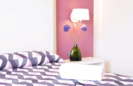 Purple Hotel Ibiza room: Bed with briefs and camera. Gay travel lodging with purple accents, modern design, and amenities.