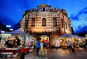 The Red House Taipei in Ximending's gayborhood, a tourist hotspot. Night view of the historic building with market stalls outside.