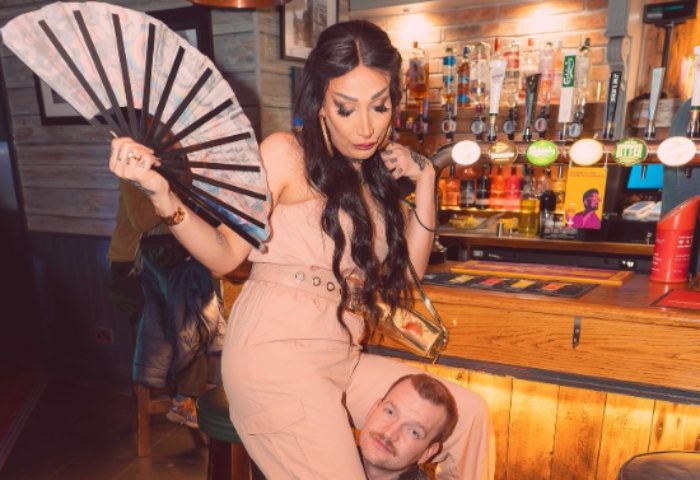 Drag queen sits on a man at The Rem Bar, Manchester. The bar is in the background. Gay travel advice.
