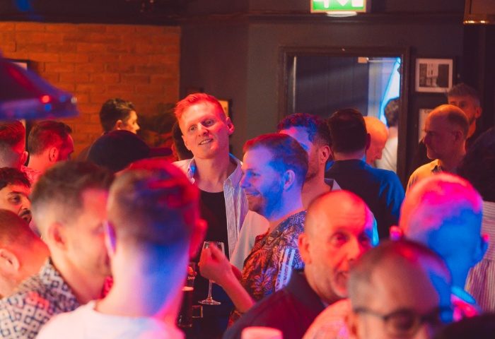 Gay men socializing at The Rem Bar in Manchester. A vibrant nightlife scene with men enjoying drinks and conversation in a lively atmosphere.