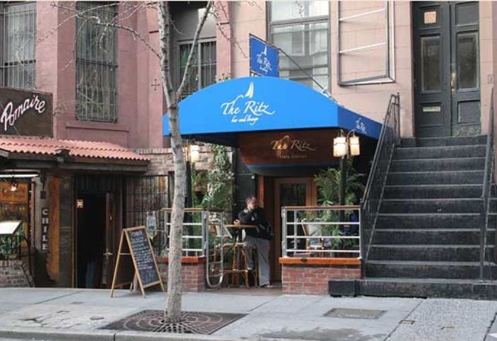 The Ritz Bar and Lounge in New York City. Gay travel destination with blue awning, outdoor seating, and a welcoming vibe for gay men.