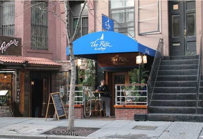 The Ritz Bar and Lounge in New York City. Gay travel destination with blue awning, outdoor seating, and a welcoming vibe for gay men.
