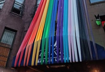 The Ritz Bar and Lounge in New York, a gay travel destination, is decorated with rainbow streamers for Pride. A welcoming gay bar.