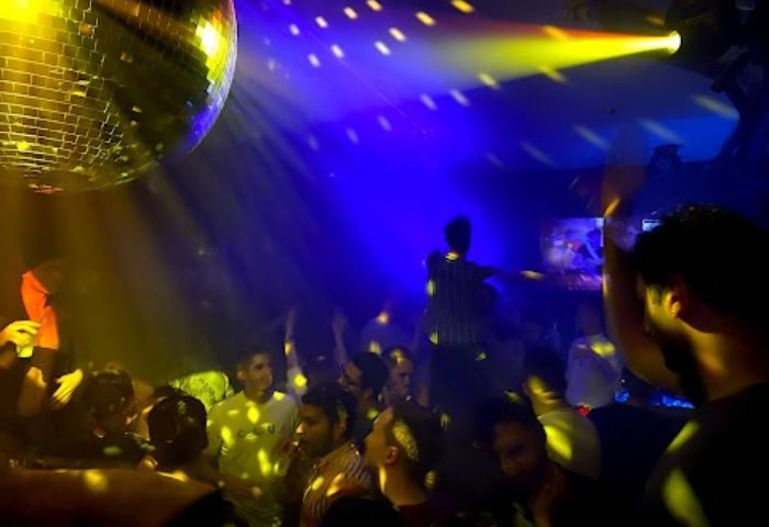 The Ritz Bar and Lounge in New York: A crowded gay bar with a mirror ball, blue and yellow lights, and men dancing. Gay travel advice.