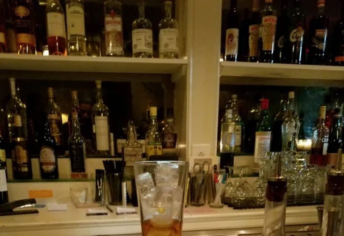 The Rosemont Chill Gay Bar in New York: Bar scene with liquor bottles on shelves, cocktail glass with ice, ready for gay nightlife.