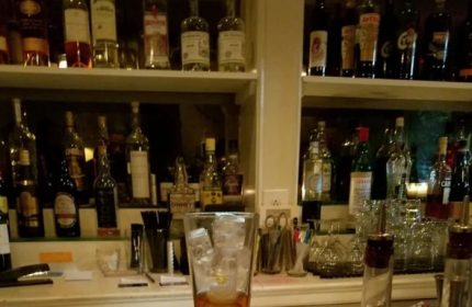 The Rosemont Chill Gay Bar in New York: Bar scene with liquor bottles on shelves, cocktail glass with ice, ready for gay nightlife.