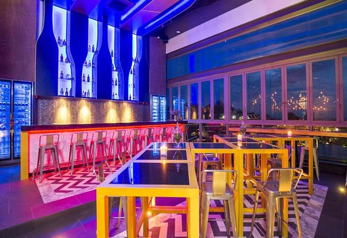 The SIS Kata Resort gay-friendly hotel bar in Patong. Modern design with blue lighting, tables, and chairs. Gay travel in Phuket.
