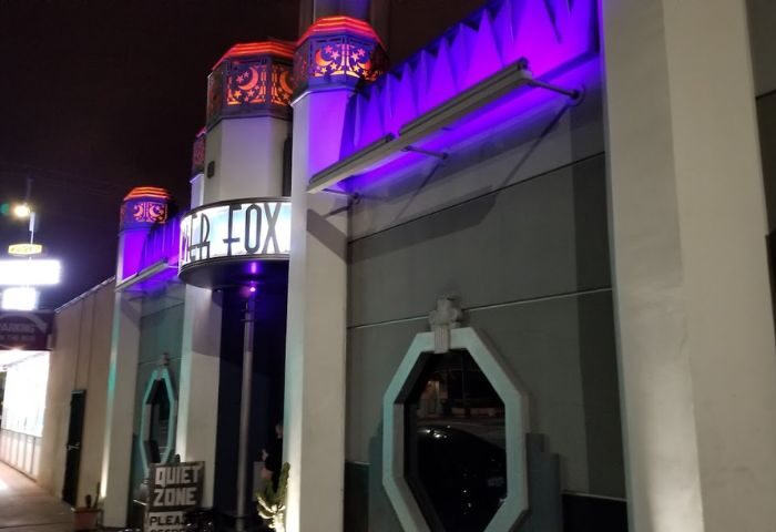 The Silver Fox location at night. Gay travel advice for men. Neon lights illuminate the building's facade. A Quiet Zone sign is visible.