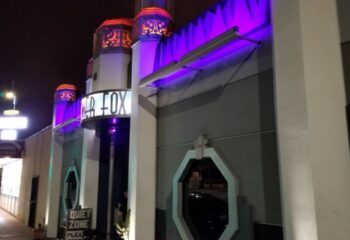 The Silver Fox location at night. Gay travel advice for men. Neon lights illuminate the building's facade. A Quiet Zone sign is visible.
