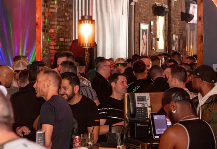 Crowded scene inside The SoFo Tap, a popular gay bear bar in Chicago. Men are socializing at the bar, enjoying the lively atmosphere.