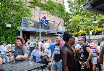 Outdoor patio at SoFo Tap, a Gay Bear Bar in Chicago. Men and women are socializing, drinking, and enjoying the summer weather.