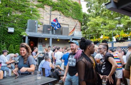 Outdoor patio at SoFo Tap, a Gay Bear Bar in Chicago. Men and women are socializing, drinking, and enjoying the summer weather.