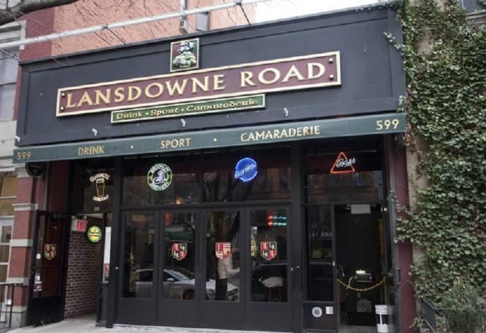 Lansdowne Road: The Spot in New York. A gay-friendly bar with Drink, Sport, Camaraderie signage. Neon beer signs adorn the entrance.