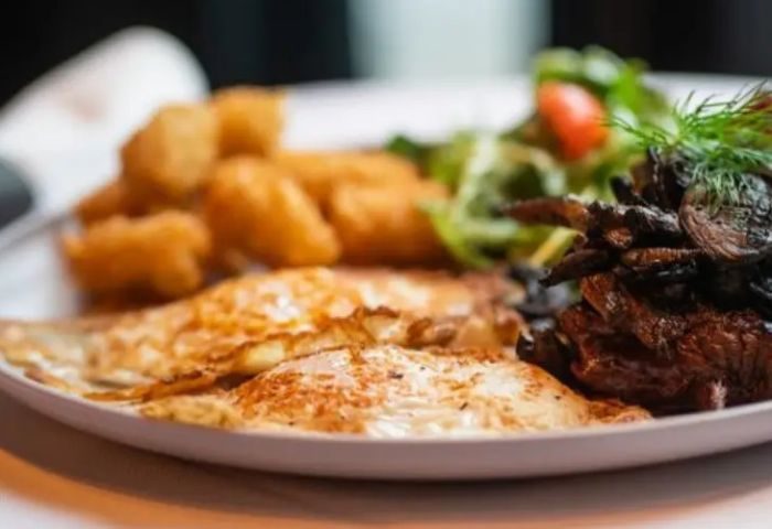 New York dining: Plate with fried eggs, fried potatoes, mushrooms, and salad. A delicious meal at The Spot in New York.