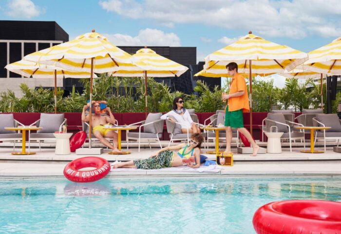 Gay Hotel, The Standard, Bangkok Mahanakhon pool scene. People lounge poolside under umbrellas, enjoying the sun at this gay-friendly hotel.