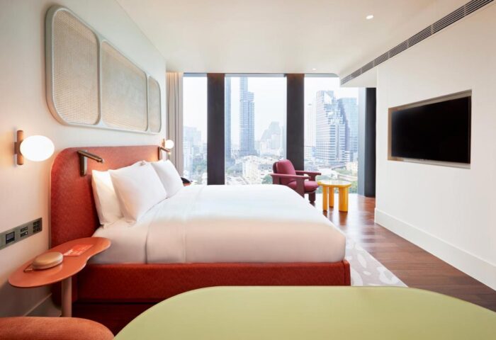 The Standard Bangkok Mahanakhon hotel room. Luxury gay hotel with city view. Modern design, red accents, and comfortable bed. Gay travel.