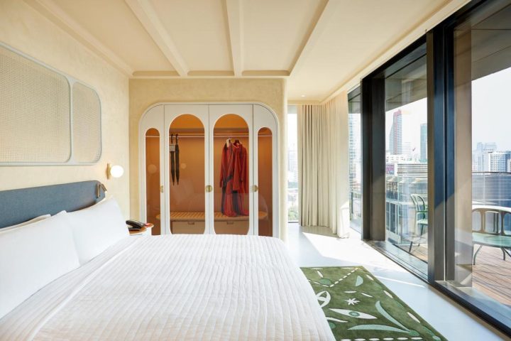 The Standard Bangkok Mahanakhon hotel room. Modern design with bed, closet, and city view. Gay travel in Silom, Thailand.