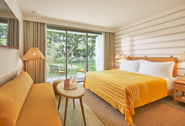 The Standard Hua Hin hotel room. Balcony view, yellow accents, bed, and couch. Gay travel destination.