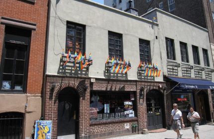 The Stonewall Inn, New York. Historic gay bar with rainbow flags, a landmark for LGBTQ+ travel. Gay men travel advice in NYC.
