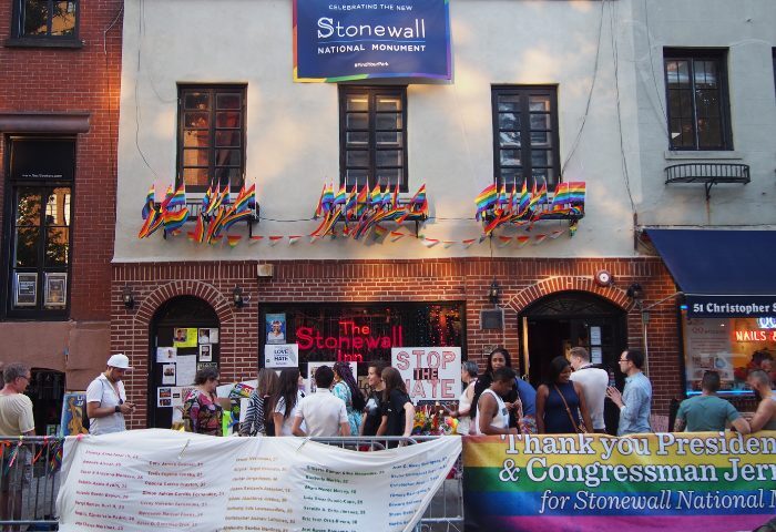 The Stonewall Inn in New York, a gay bar and historic landmark, is decorated with rainbow flags. People gather outside the Stonewall National Monument.